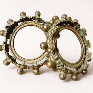 Può includere: Antiche montature per occhiali color bronzo con un design floreale e sferico decorativo. Le montature hanno una forma circolare e sono collegate. Il metallo ha un aspetto invecchiato.