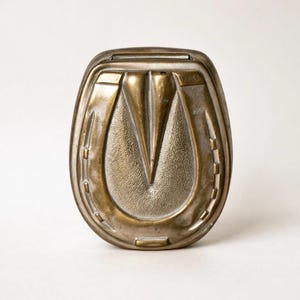 Puede incluir: Una taza de cerámica blanca con un asa negra y el texto "But First, Coffee" en negrita negra. La taza está sobre una superficie de madera. La taza mide aproximadamente 10 cm de alto.