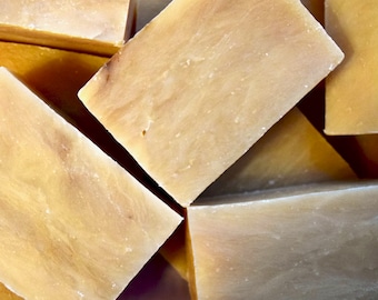 May include: Close-up of several bars of handmade soap. The soap is a light beige color and has a marbled appearance.