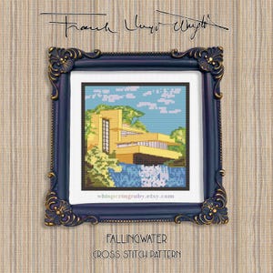May include: A framed cross-stitch pattern of Fallingwater, a famous architectural design. The artwork features a yellow building with blue water and sky, set in a dark blue and gold ornate frame. The text "Fallingwater Cross Stitch Pattern" is at the bottom.