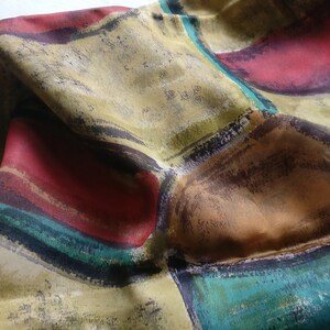 Könnte beinhalten: Ein Seidentuch mit einem abstrakten Design mit geometrischen Formen in Rot-, Braun-, Grün- und Gelbtönen.