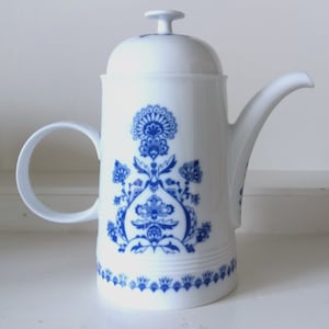 Könnte beinhalten: Weiße Porzellan-Kaffeekanne mit blau-weißem Blumenmuster. Die Kanne hat einen Deckel und einen Henkel.