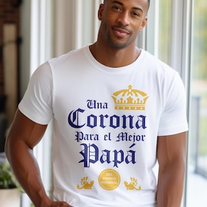 Puede incluir: Camiseta blanca con un gráfico azul y dorado que dice "Una Corona Para el Mejor Papá" con una corona sobre la palabra "Corona" y un pequeño logotipo debajo del texto que dice "Del Mundo Mundial".