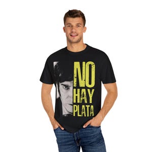 Puede incluir: Camiseta negra con un estampado gráfico amarillo de la cara de un hombre y el texto "NO HAY PLATA".