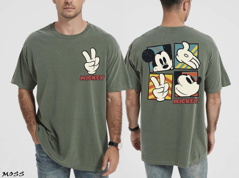 May include: A moss green t-shirt with a white peace sign and the word "Mickey" in red. The back of the shirt features Mickey Mouse imagery in a square pattern. The t-shirt is a relaxed, casual style.
