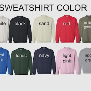 May include: A display of sweatshirts in various colors, including white, black, sand, red, military green, royal blue, forest, navy, light pink, and sport grey. The text "SWEATSHIRT COLOR" is at the top.