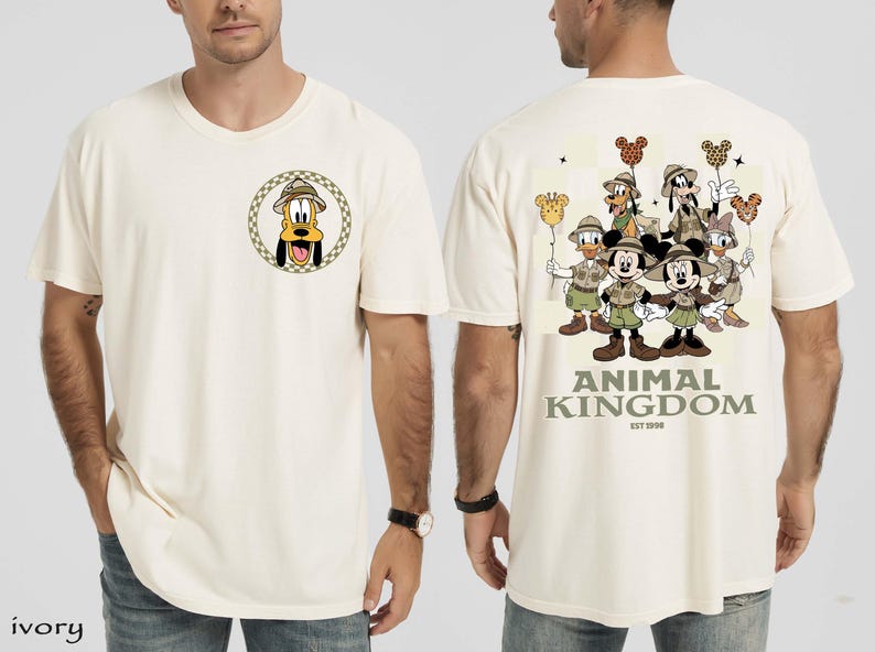 May include: Ivory t-shirt with a Pluto graphic on the front, wearing a safari hat. The back displays Disney characters like Mickey and Minnie Mouse, Donald Duck, and Goofy. The text "ANIMAL KINGDOM EST 1998" is printed below the characters.