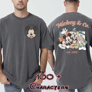 May include: Dark gray t-shirt featuring Mickey Mouse on the front and a group of Disney characters on the back. The back of the shirt has the text "Mickey & Co. - Est. 1928-".