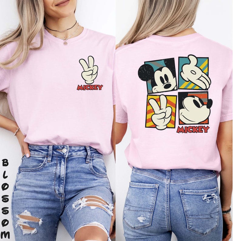 May include: Pale pink t-shirt with a Mickey Mouse graphic. The front shows a peace sign made with Mickey's hand and the word "Mickey". The back has a four-square design with Mickey's face and hand. The word "Mickey" is also printed on the back.