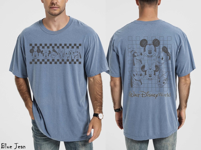 May include: A blue jean colored t-shirt featuring a front graphic of Disney characters in a black and white checkered band. The back displays a larger grid pattern with character faces and the text Walt Disney World in a dark script font.