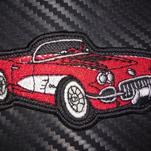 May include: Red embroidered patch of a classic convertible sports car with a white interior and chrome accents.