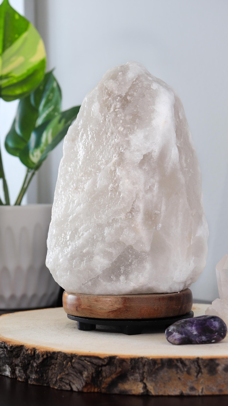 May include: A large, white Himalayan salt lamp with a wooden base. The lamp is sitting on a wooden slice.