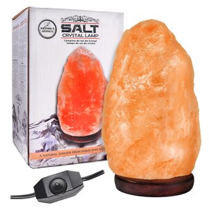 May include: A natural Himalayan salt crystal lamp with a warm orange glow. The lamp is on a wooden base and has a cord with a switch. The box reads "Salt Crystal Lamp" and "A Natural Ionizer from Himalayan Salt".