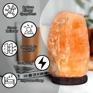May include: A large, orange Himalayan salt lamp with a wooden base. The lamp is on a white surface and there are several icons around it that list the benefits of using a salt lamp, including reducing allergy symptoms, stress relief, natural air purification, energising, and improving sleep.