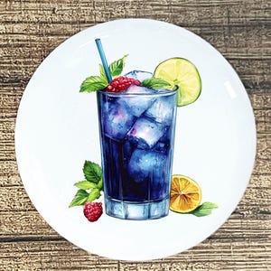 May include: A white ceramic plate featuring a watercolor illustration of a refreshing blue cocktail. The drink is garnished with raspberries, mint leaves, and a lime slice. A blue straw is in the glass. The plate is on a wooden surface.