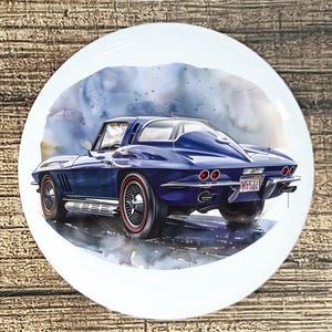 May include: A round, white decorative plate featuring a watercolor painting of a classic blue sports car. The car has red-trimmed wheels and a license plate. The background has a watercolor wash effect.