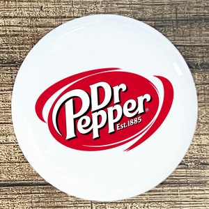 May include: White round sticker with a red oval containing the Dr Pepper logo in white text with the words "Est. 1885" below the logo.