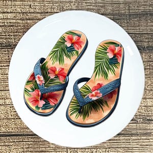 May include: A white ceramic plate featuring a pair of flip-flops. The flip-flops have a tropical design with pink hibiscus flowers and green palm leaves on a peach background. The straps are blue.