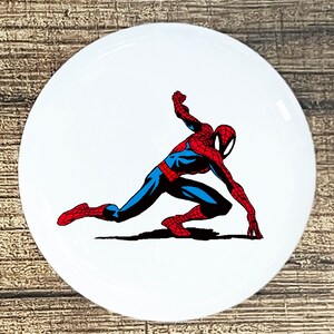 May include: A red and blue cartoon illustration of Spiderman in a crouching pose with his arms outstretched.
