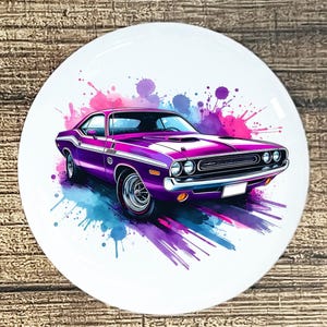 May include: A purple classic car illustration on a white circular surface. The car has white racing stripes and is set against a backdrop of colorful paint splatters in shades of pink, blue, and purple. The image is on a wooden surface.