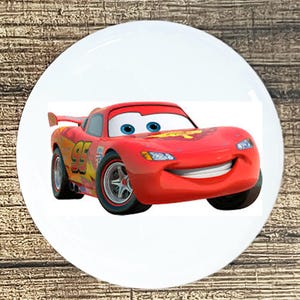 May include: A red cartoon race car with a big smile and black wheels. The car has a yellow number 95 on the side.