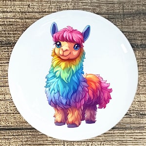 May include: A colorful llama illustration on a white, round surface. The llama has a rainbow-colored coat, pink hair, and blue ears. The background is a wooden surface.