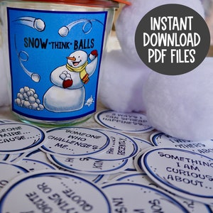 May include: A glass jar with a blue label that says "Snow Think Balls" and a cartoon snowman throwing snowballs. The jar is filled with white cotton balls. There are several white paper circles with blue text on them scattered around the jar. The text on the circles includes phrases like "Someone I admire because..." and "Something I am curious about..."