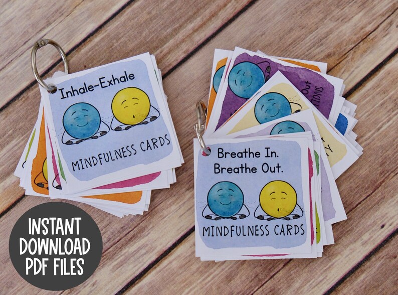 Puede incluir: Un juego de tarjetas de atenci&oacute;n plena de colores con ilustraciones de dos caras de dibujos animados. Las tarjetas est&aacute;n unidas con un anillo plateado. El texto en las tarjetas dice "Inhala-Exhala" y "Inhala. Exhala." Las tarjetas est&aacute;n etiquetadas como "Tarjetas de atenci&oacute;n plena".