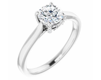 May include: A silver engagement ring with a round, clear center stone and a halo of smaller stones.