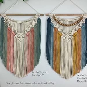 Pode incluir: Dois pain&eacute;is de macram&eacute; suspensos em varas de madeira. A pe&ccedil;a da esquerda apresenta cord&otilde;es de algod&atilde;o em verde s&aacute;lvia, rosa seco e creme. A pe&ccedil;a da direita inclui cord&otilde;es azul-marinho, amarelo mostarda e creme com contas de madeira de &aacute;cer.