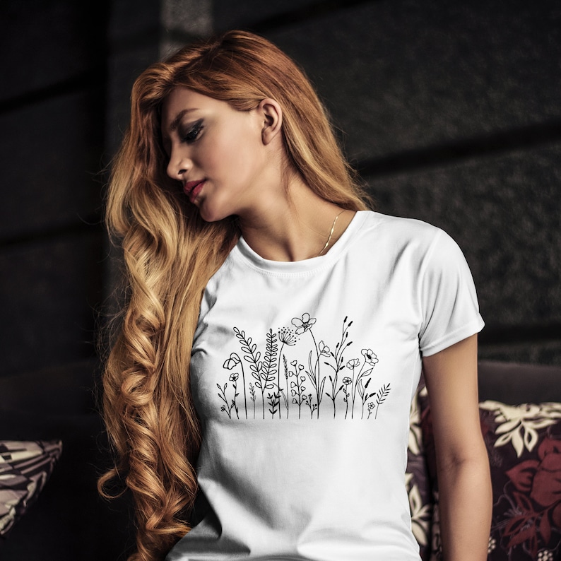Puede incluir: Camiseta blanca con un dibujo de l&iacute;nea negra de un ramo de flores.