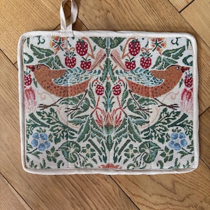 May include: A rectangular pot holder with a cream border and a hanging loop. The central design showcases two birds, red berries, green foliage, and blue flowers in a symmetrical pattern. The pot holder is approximately 20 cm x 25 cm.