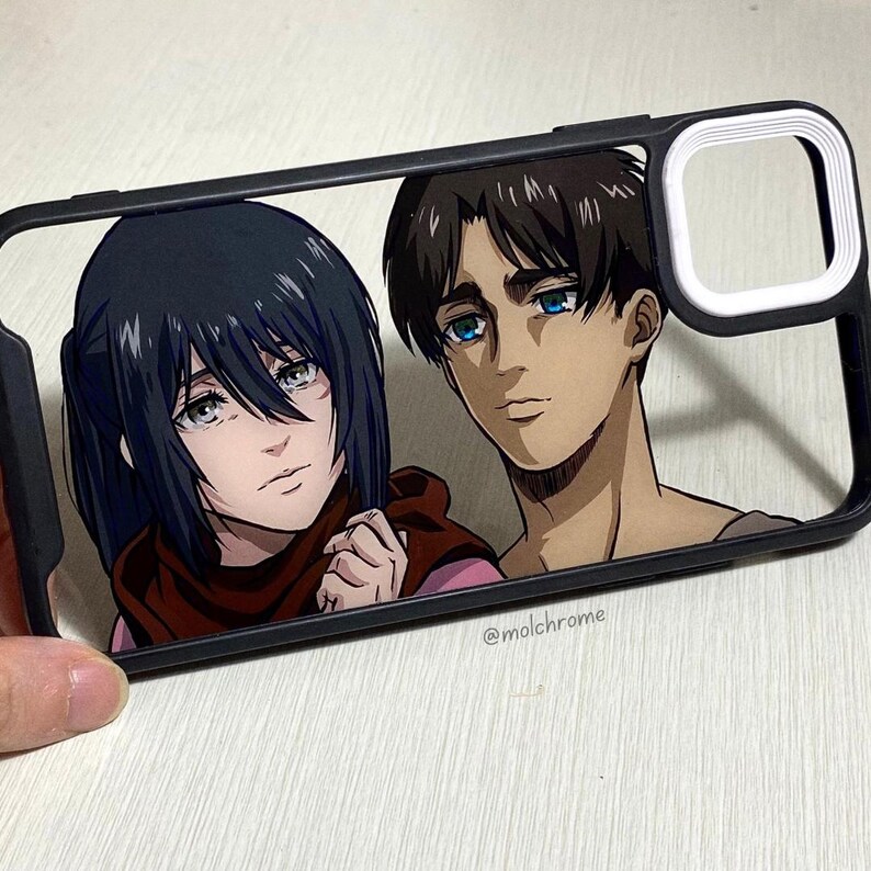Pu&ograve; includere: Una custodia per telefono nera con un bordo bianco attorno all'obiettivo della fotocamera. La custodia presenta un'immagine stampata di due personaggi anime, uno con i capelli neri e l'altro con i capelli castani. Il testo "@molchrome" &egrave; stampato sul fondo della custodia.