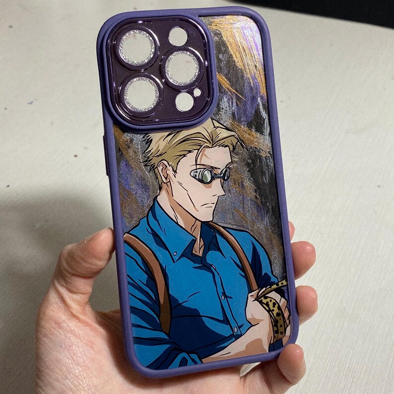 Pu&ograve; includere: Una custodia per telefono viola con un designo astratto oro e nero. La custodia presenta un'immagine stampata di un uomo con i capelli biondi che indossa occhiali e una camicia blu.