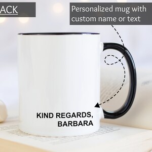 Puede incluir: Taza de cer&aacute;mica blanca con asa y borde negros. La taza tiene el texto "KIND REGARDS, BARBARA" impreso en la parte posterior.
