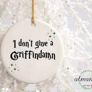 May include: White ceramic Christmas ornament with black text that reads "I don't give a Griffinday" and small black stars.