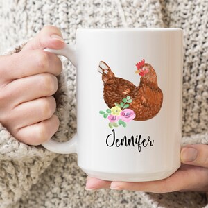 May include: White ceramic mug with a brown chicken illustration and pink and yellow flowers. The mug has the name "Jennifer" written on it.