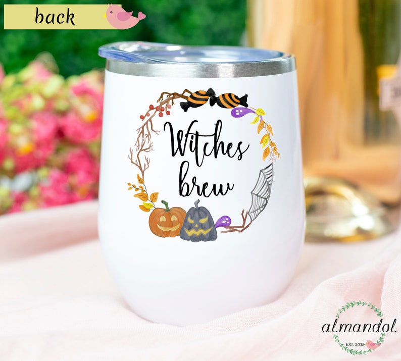 May include: White stainless steel tumbler with a black and orange Halloween themed design. The design features a wreath with pumpkins, candy corn, and a spider web. The text "Witches Brew" is written in black cursive lettering.