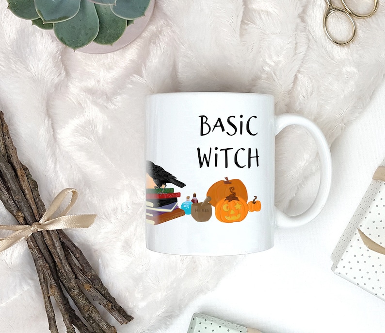Pode incluir: Caneca de cer&acirc;mica branca com al&ccedil;a preta. A caneca tem um gr&aacute;fico preto de um corvo, livros, garrafas de po&ccedil;&otilde;es e uma ab&oacute;bora. O texto "BASIC WITCH" &eacute; impresso em preto na caneca.