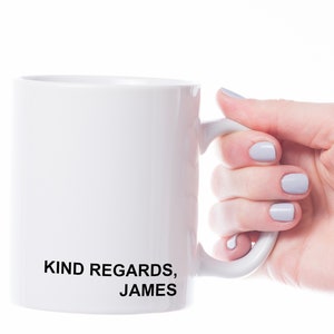 Puede incluir: Taza de cer&aacute;mica blanca con texto negro que dice "KIND REGARDS, JAMES". Una mano sostiene la taza.