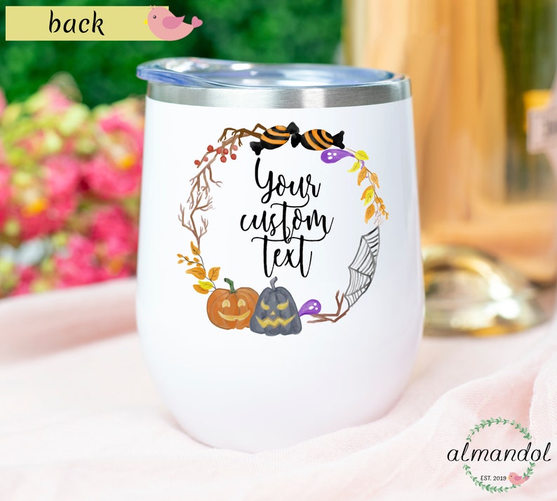 May include: White stainless steel wine tumbler with a Halloween themed design. The design features a wreath with pumpkins, candy corn, and a spider web. The text "Your custom text" is in the center of the wreath.