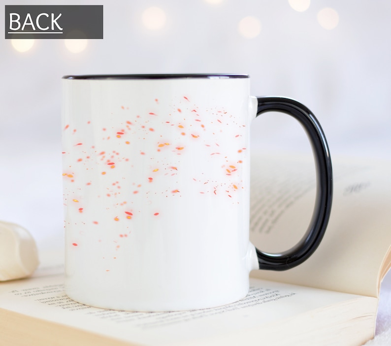 Puede incluir: Taza de cer&aacute;mica blanca con borde y asa negros. La taza tiene un dise&ntilde;o de puntos naranja y rojo dispersos en la parte delantera.