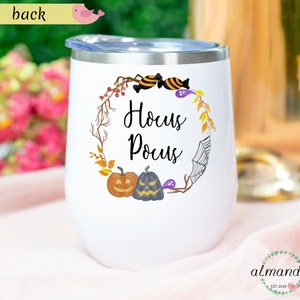 May include: White stainless steel wine tumbler with a black and white Hocus Pocus design. The design features a wreath with pumpkins, candy, and a spider web.