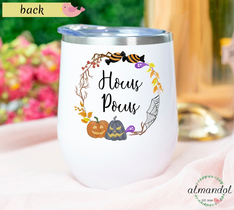 May include: White stainless steel wine tumbler with a black and white Hocus Pocus design. The design features a wreath with pumpkins, candy, and a spider web.
