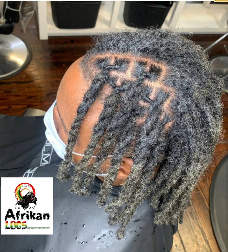 Op de afbeelding: Een persoon met grijs en zwart dreadlocks. De dreadlocks zijn gestyled in een patroon met sommige van de dreadlocks aan elkaar gebonden.