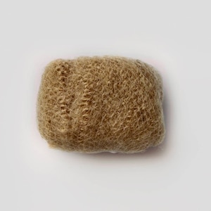 May include: A close-up of a light brown hair bun, made of synthetic hair fibres, for creating a bun hairstyle.