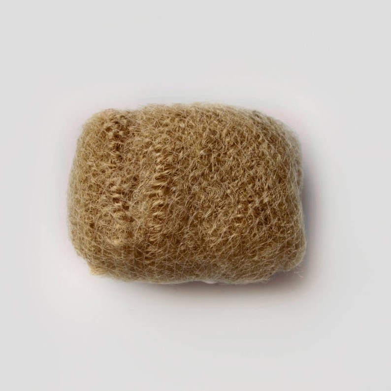 May include: A close-up of a light brown hair bun, made of synthetic hair fibres, for creating a bun hairstyle.
