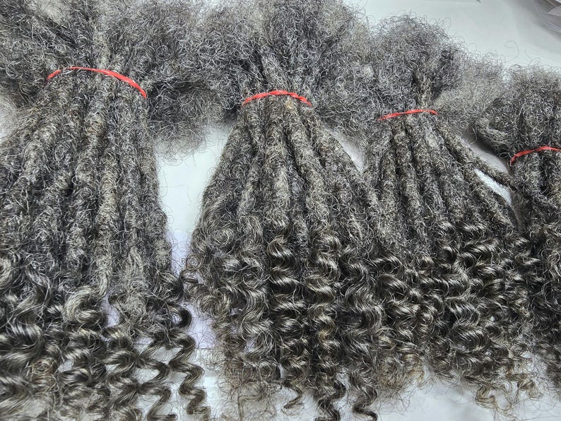 Op de afbeelding: Een bundel grijze, krullende dreadlocks haarverlengingen. Het haar is lang en dik, met een natuurlijke, licht golvende textuur.