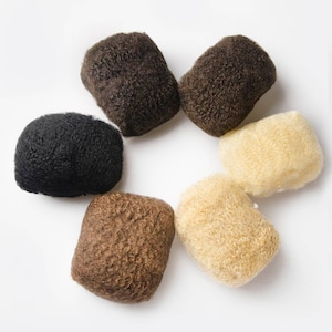 May include: Six hair pieces in different shades of brown and blonde. The hair pieces are arranged in a circle on a white background.