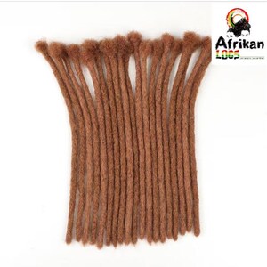 May include: A bundle of brown dreadlocks, arranged vertically against a white background. The dreadlocks are a warm, medium brown color and appear to be made of a textured material. The logo "Afrikan Loops" is visible in the upper right corner.